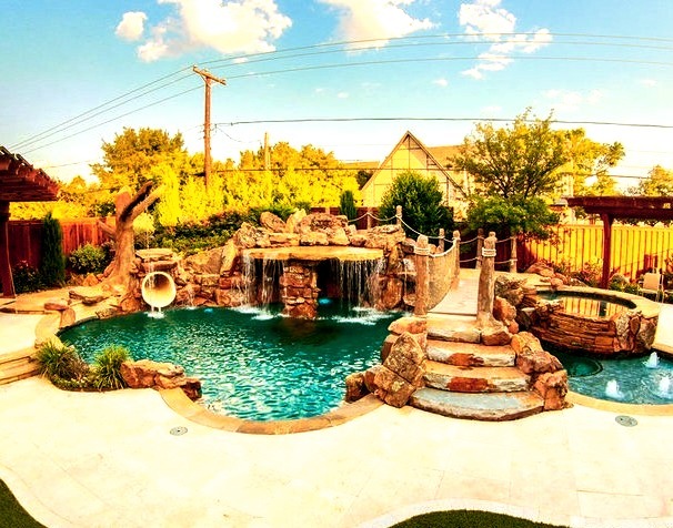 Large island style backyard stone and custom-shaped water slide photo
